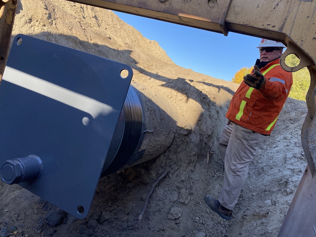 Worker with pipe in ditch