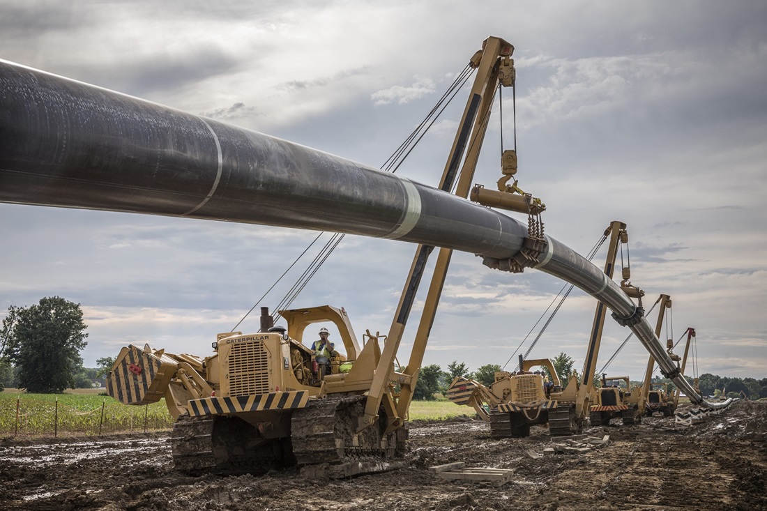 cranes lowering pipe into trench