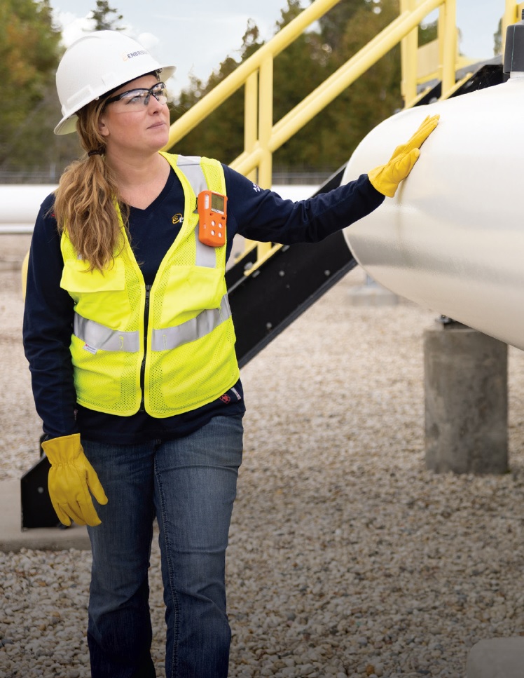 Woman in safety gear inspecting a pipe