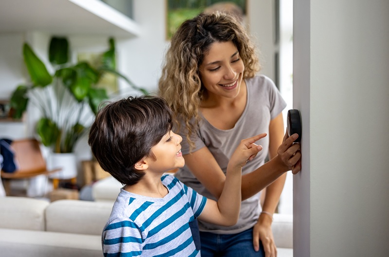 Mother and boy adjust thermostat