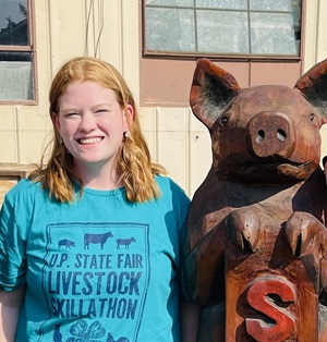 Teenage 4-H winner with a wood statue of a pig